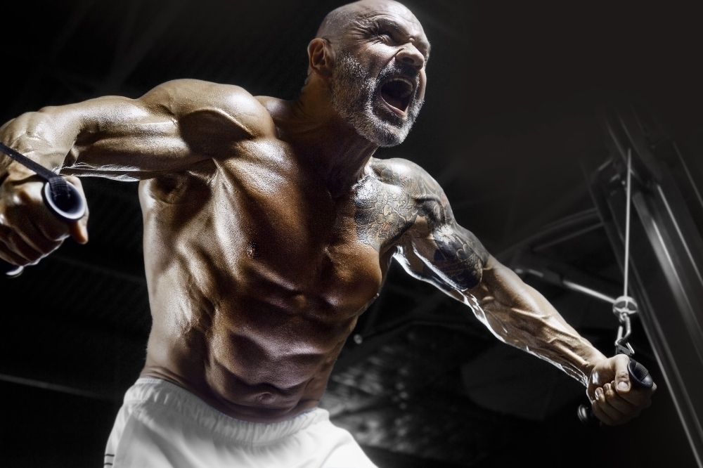 Brutal and muscular strong bodybuilder athletic man pumping up muscles at workout in the gym