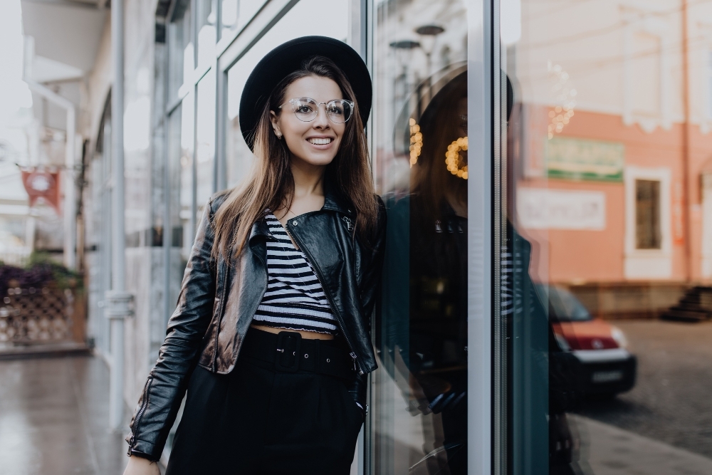 Pretty happy smiling girl walks on the street in black leather jacket after rain